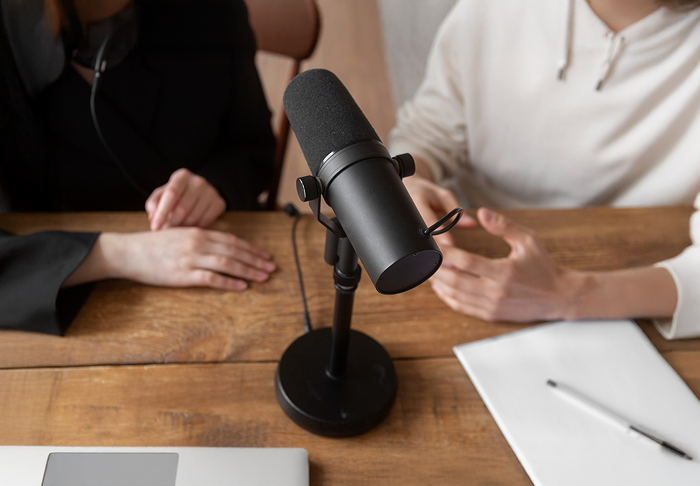 Two Podcasters Sitting Around A Microphone