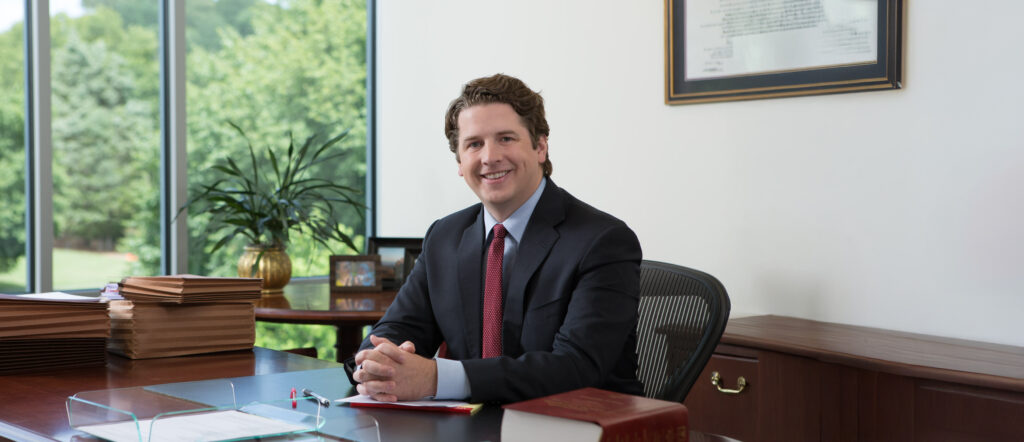 Wesley Lyon Smiling Sitting At His Desk In Office